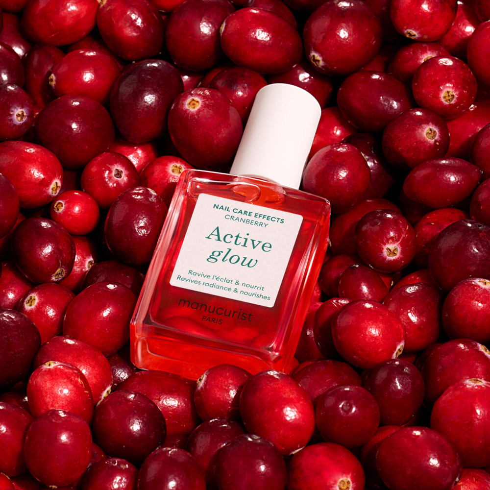 Active Glow Cranberry Manucurist бутилка върху червени боровинки