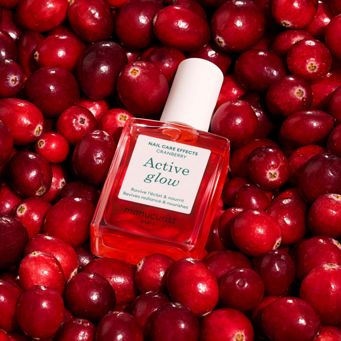 Active Glow Cranberry Manucurist бутилка върху червени боровинки